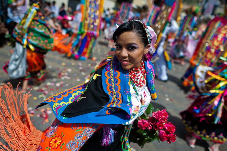 A dancer (danzante), holding flowers, takes part in the religious parade within the Corpus Christi festival in Pujilí, Ecuador, 10 June 2012. Every year in June, thousands of people gather in a small town of Pujili, high in the Andes, to celebrate the Catholic feast of Corpus Christi. Introduced originally during the Spanish conquest of South America, this celebration merges Catholic rituals of Holy Communion with the traditional Andean harvest and sun festivities (Inti, the Inca sun god). Women dancers perform wearing brightly colored costumes while men dancers wear chest ornaments and heavy elaborate headdresses adorned with mirrors, jewelry, or natural items (shells). Being a dancer in the Corpus Christi ceremonial parade (El Danzante) is considered an honour and a privilege by the indigenous people in Ecuador.