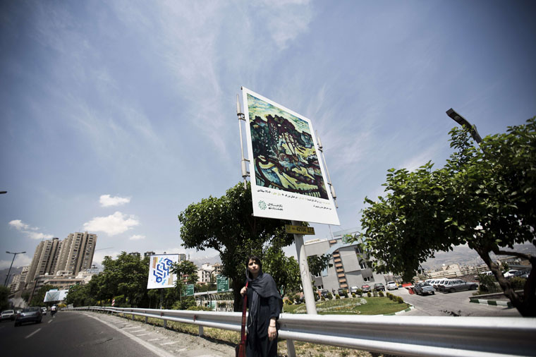 An Iranian woman waits for a taxi under a billboard displaying a "Trees at Estaque" painting by French painter Georges Braque (1882-1963) on northern Tehran's Modares highway on May 9, 2015. More than 1,500 reproductions of  art classics, including Vincent Van Gogh's sunflowers, Edward Munch's The Scream and The Blue Window by Henry Matisse, line the streets and highways of Tehran until mid-May as part of a cultural project organised by the Iranian capital's municipality under the title: "A Gallery as Big as a Town".  AFP PHOTO/BEHROUZ MEHRI